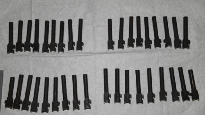 Rows of black gun parts laid out on a white sheet