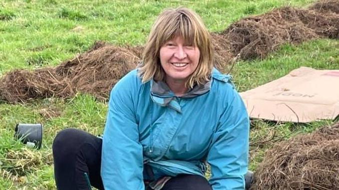 Dixie Darch smiling at the camera in a grassy field