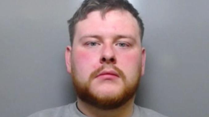 Mugshot of Gavin Jackson. He has short dark hair and a thick ginger beard.
