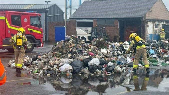 Firefighters monitoring a pile of waste at the depot