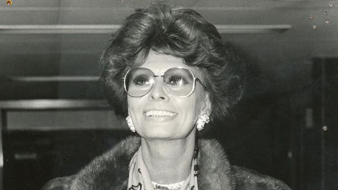 Sophia Loren wearing large glasses, a patterned scarf, large earrings and a fur coat