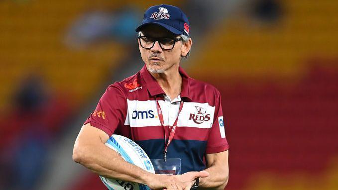 Queensland Reds boss Les Kiss carrying a rugby ball