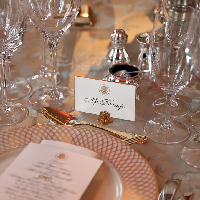 A dinner setting with gold cutlery and a place card that reads Mr Trump