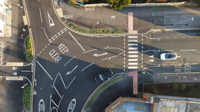 An aerial view of a junction with fresh road markings, cycle lanes and a pedestrian crossing.