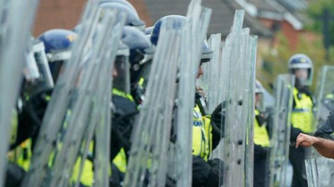 Line up of police with riot shields in summer 2024