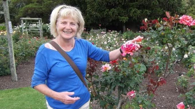 Danielle Carr-Gomm in blue top standing near rose garden.