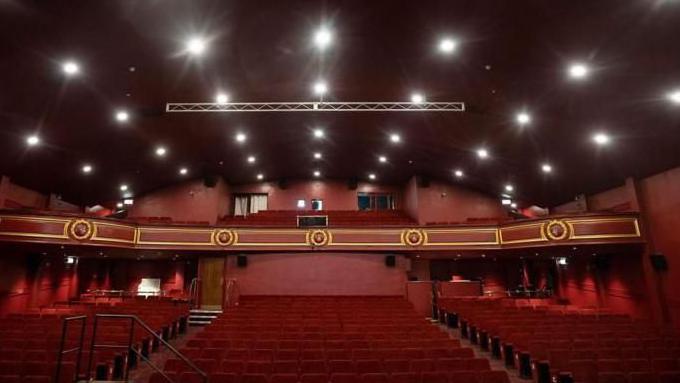 Inside the Empire's auditorium which has red seats and red walls. There is a balcony with additional seating.