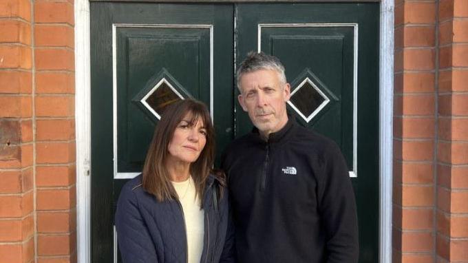 Lisa and Marc Thomas standing outside a door.

