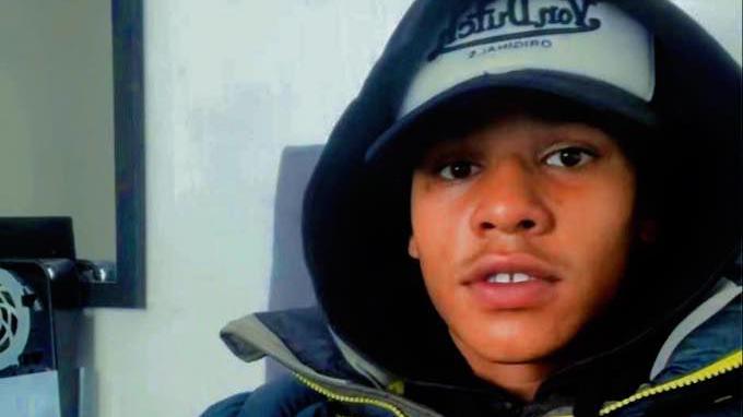A selfie photograph of Devon Simmonds shows him wearing a baseball cap with his hood up. He is staring directly at the camera.