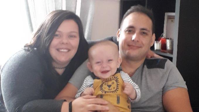 Sammie Lee and Karl Lee sitting next to each other with their baby son in Karl Lee's lap.