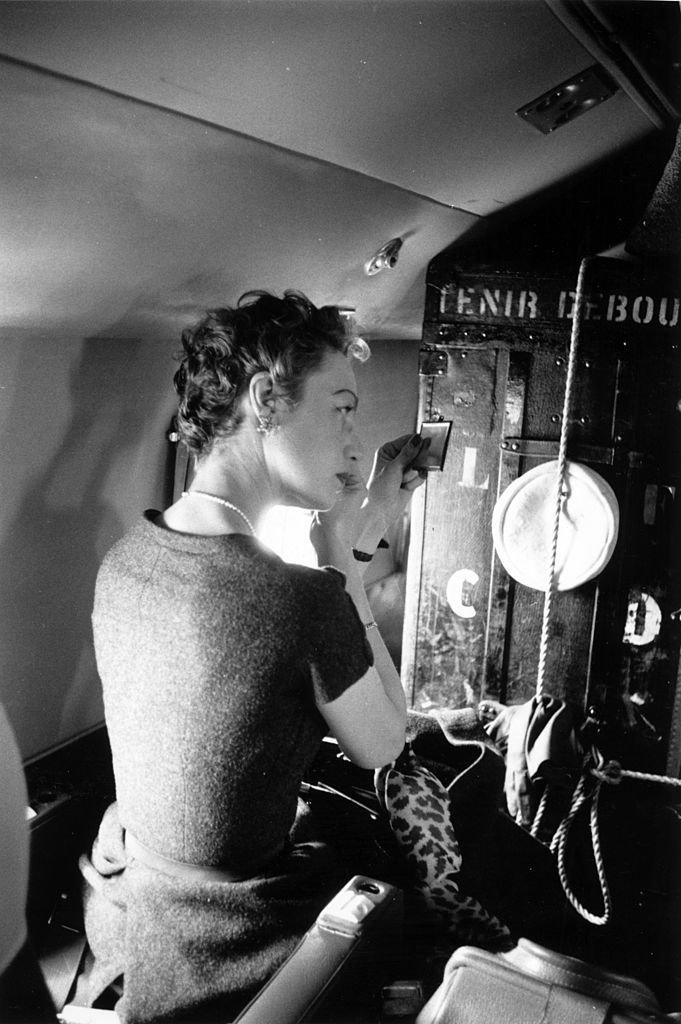 21st May 1955: A model applying her make-up during a flight to Scotland to take part in the Christian Dior fashion show on behalf of the charity 'Friends of France'.