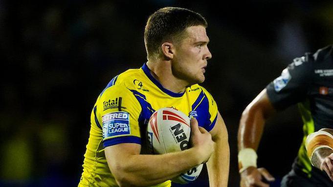 Warrington Wolves wing Jake Thewlis, in yellow and blue, carries the ball 