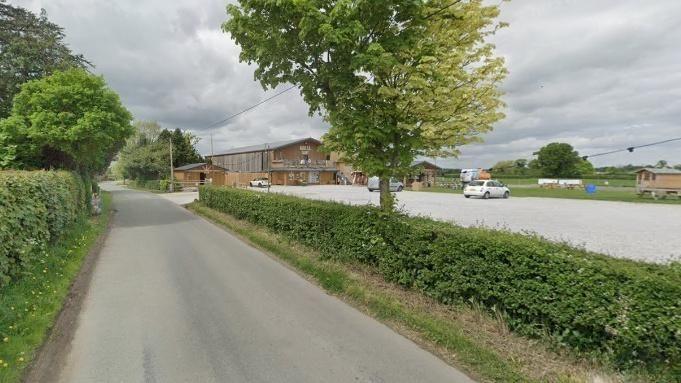 A screenshot from Google Streetview of a road alongside a farm and farmhouse. 