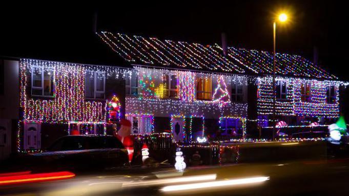 A row of terrace house with coloured Christmas lights on them 