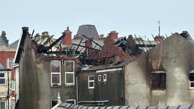 The remains of a derelict hotel after it was devastated by a huge fire. The roof is missing, with only charred black rafters remaining.