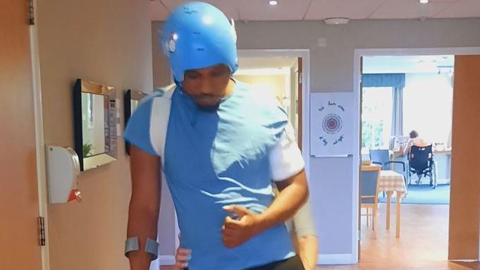 Tharel Thompson, pictured as he goes through rehab, wearing a helmet to protect his injured head.