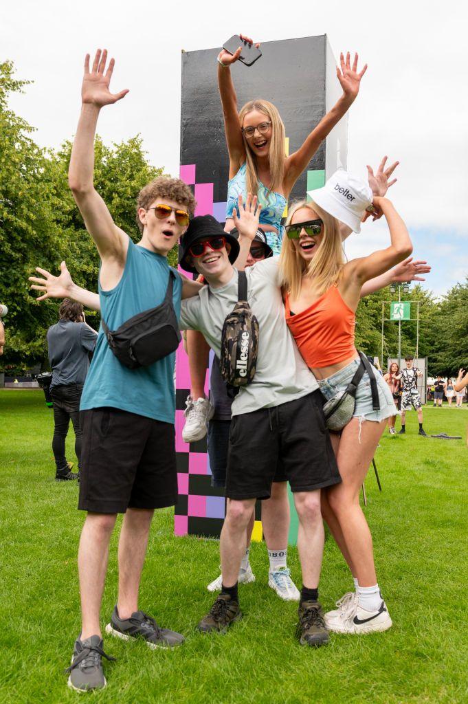 Two boys and two girls pose in front of a Rockstar energy sign at Trnsmt festival