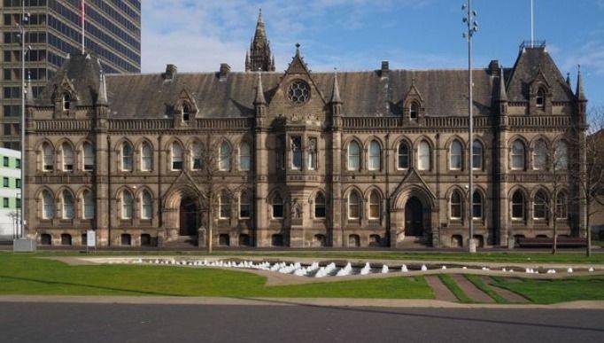 Middlesbrough Town Hall, a large gothic building in sandstone with a pitched slate roof. There are two rows of hight arched windows and small pointed towers.