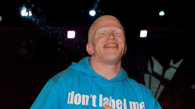 Darnell Swallow smiles as he as he is evicted from the Big Brother house. He wears a light blue hoodie. 