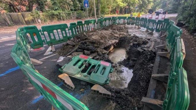 Roadworks at Deepcut Bridge Road in Surrey. Green plastic fencing around a water leak.