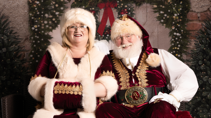 Sharon and Allan Evans dressed as Santa and Mrs Claus, sat together with festive garlands in the background