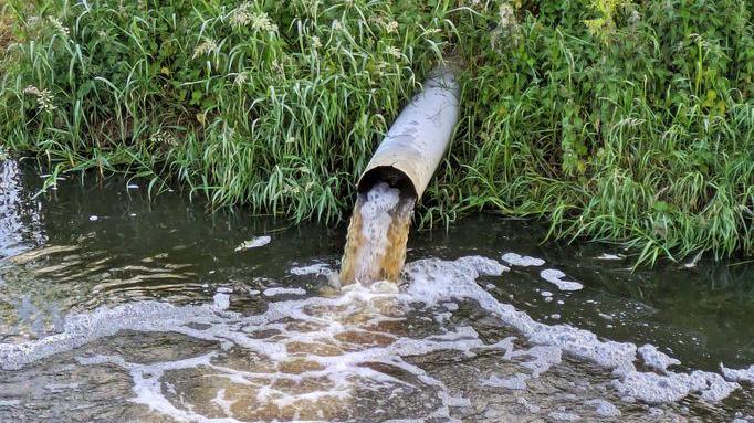Outflow pipe discharging waste into river.