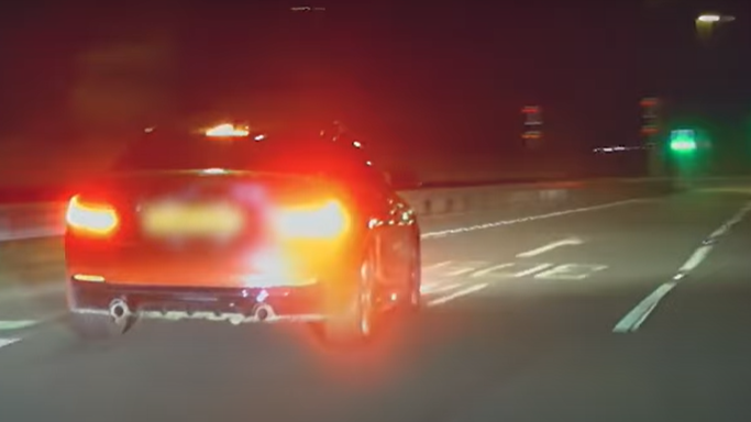 Police dashcam photo of an orange BMW driving anti-socially on a road