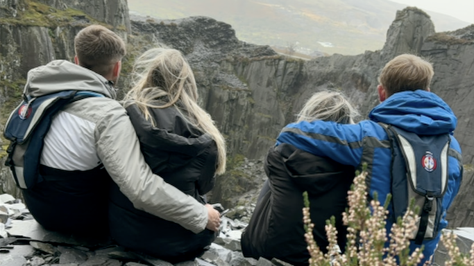 Llun o ddau gwpl yn eistedd mewn chwarel gyda'u cefnau at y camera.