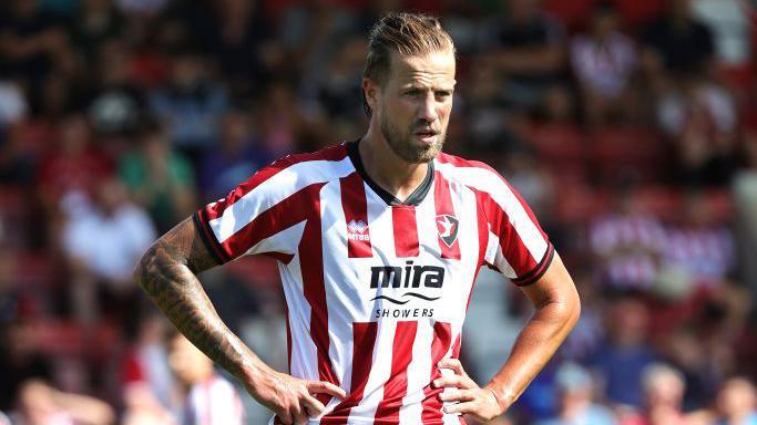 Harry Pell standing with his arms on his hips during Cheltenham's pre-season match with Northampton