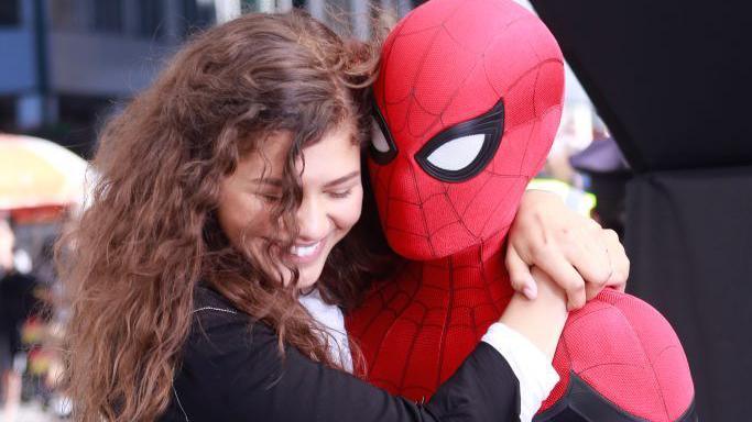 Zendaya hugging Tom Holland who is wearing a Spider-Man costume