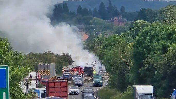 a coach on fire on a busy road