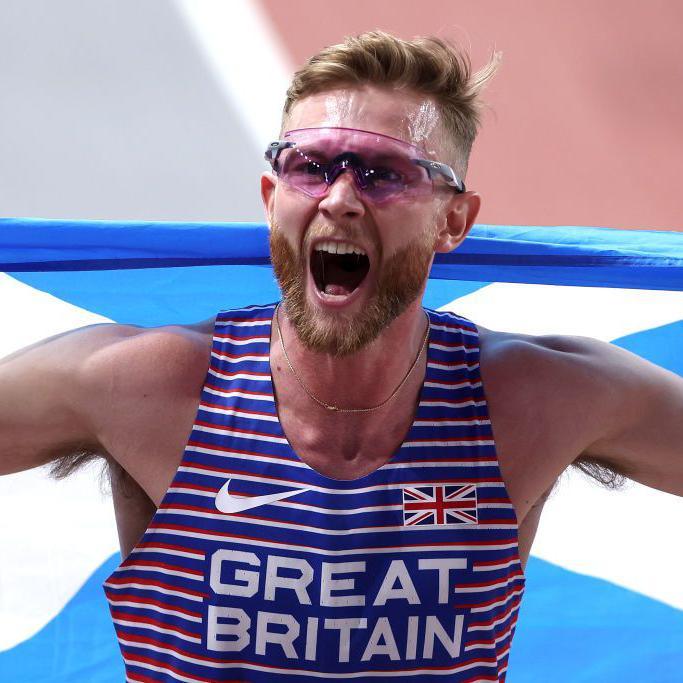 Josh Kerr celebrates winning the world indoor 3000m title in Glasgow by holding the Scottish flag