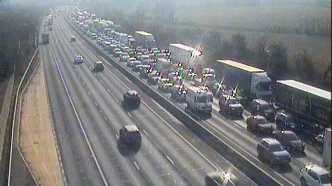 A traffic camera shows a queue stretching back towards the horizon on the M1