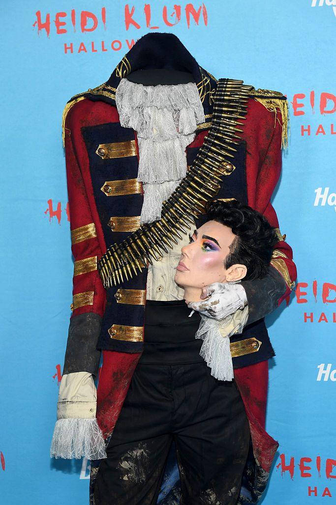 YouTuber James Charles carries his head on the carpet while wearing a 1700s era jacket
