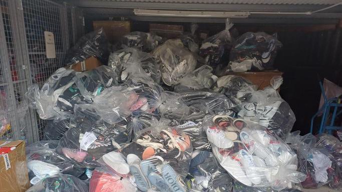 Many bags of hundreds of fake trainers in the container