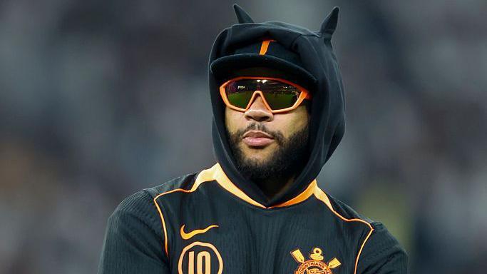 Memphis Depay wearing a black hoodie and orange glasses