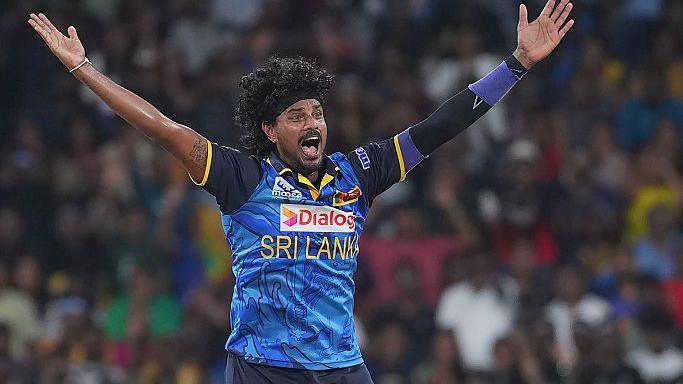 Binura Fernando with arms outstretched appealing for a wicket in a blue Sri Lanka shirt