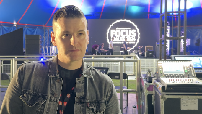 Andy Jones at Focus Wales festival in Wrexham in May 2024, inside the Llwyn Isaf big top with mixing desk behind him, and Focus Wales logo projected onto the stage behind him in white