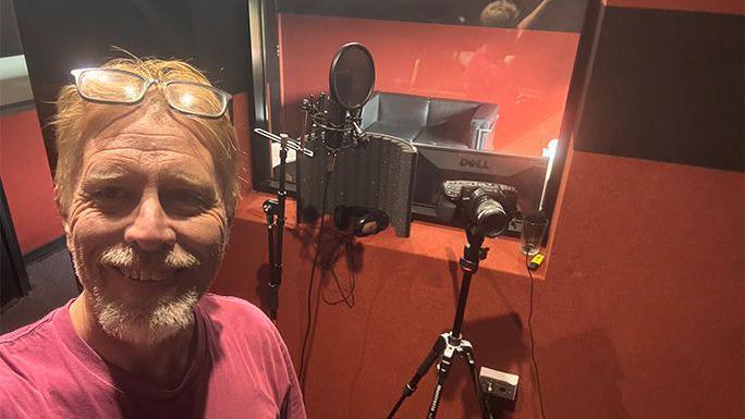 Joseph McGrail-Bateup smiling in the recording booth.