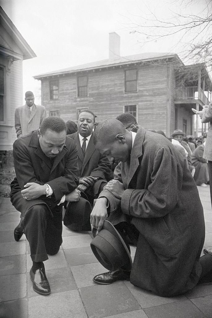 Martin Luther King Jr kneeling outside a courthouse in Alabama