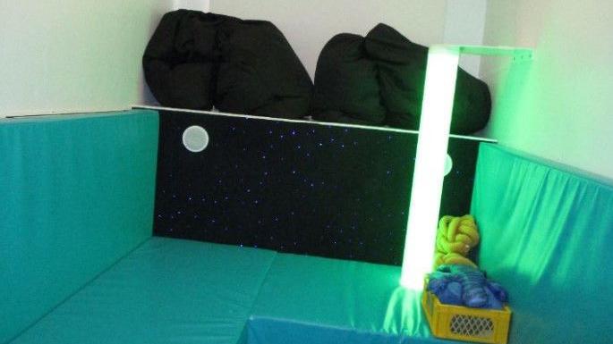 A sensory room with green lights and cushions at a prison 