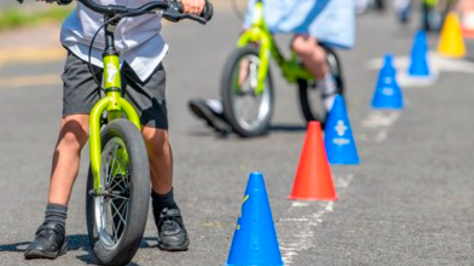 Children cycle around a cone on the street