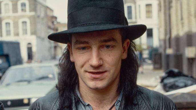 A head and shoulders archive shot from 1984 of Bono in a big black-rimmed hat arriving at the recording studio.