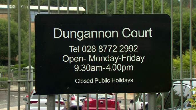 Shows a black and white sign for Dungannon court attached to an iron gate