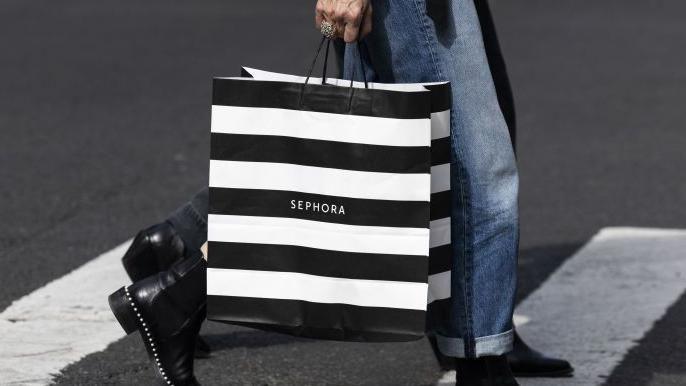 Image shows a black and white striped bag held by a woman walking across a zebra crossing. You can only see her bottom half - she is wearing jeans and black ankle boots and someone is behind her taking the same step.
