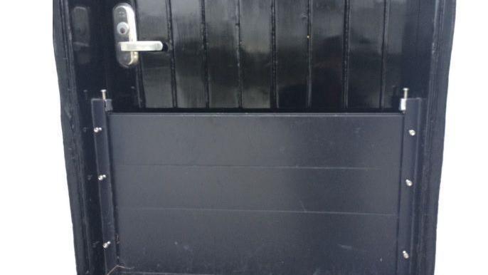 A black door with a flood barrier covering the lower portion of the doorway