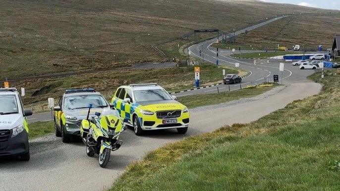 Police cars and a motorbike parked ahead of the Bungalow section of the Mountain Road