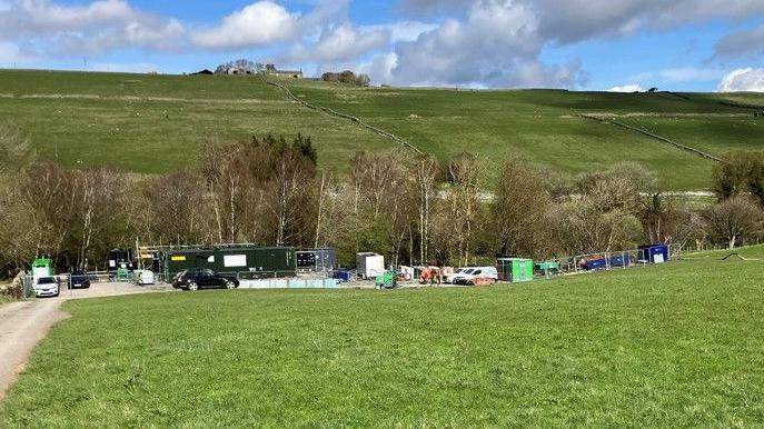 The test plant in Weardale. A number of pods and cars at the site are fenced off. It is surrounded by grassland and trees.