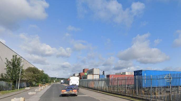 Industrial street in Leeds, with lorry and large metal containers in shot.