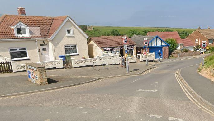 Houses and a cafe in Staithes, North Yorkshire, on a sunny day. A cafe has bunting across its entrance.